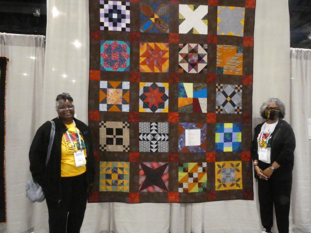 Melanie Dantzler, president of the African American Quilt Circle of Durham, N.C. and past vice president Teena Crawshaw, stand in front of the quilt 