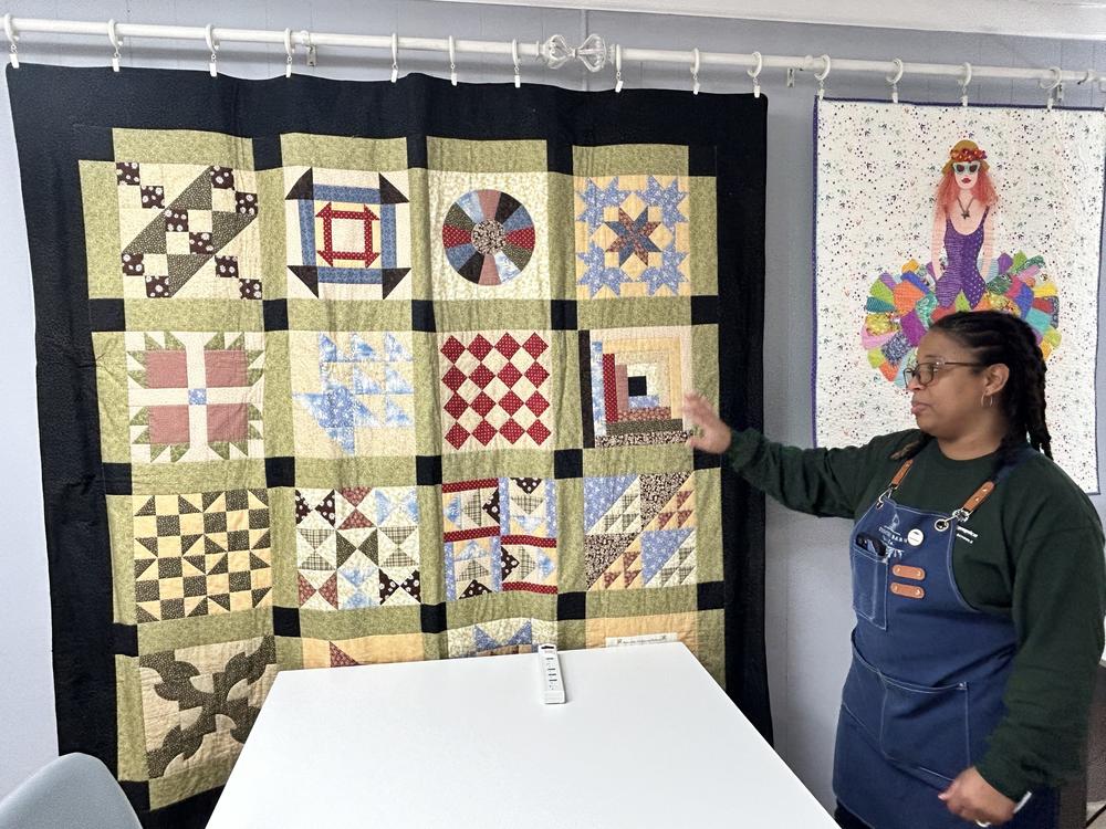 Sandra Daniel stands before an Underground Railroad Quilt Code quilt hanging in her store, Country Barn Quilt Co.