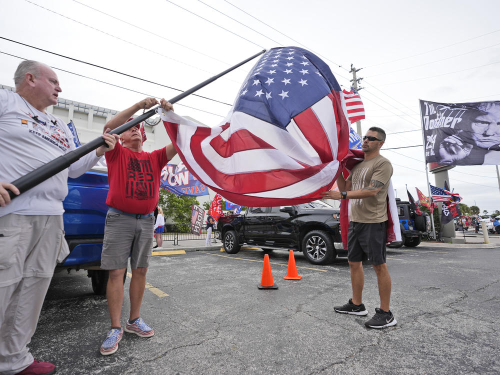 Supporters of former President Donald Trump prepare to raise a U.S. flag as they wait for his arrival Friday at the federal courthouse in Fort Pierce, Fla.