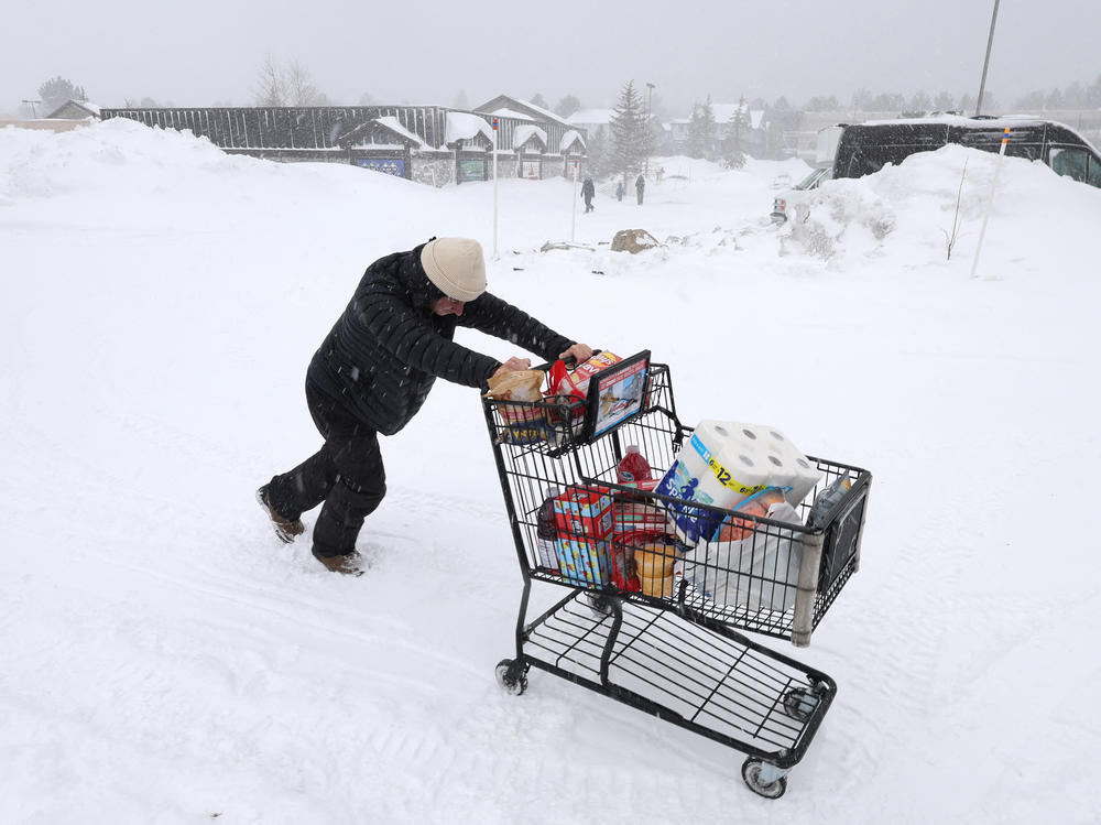 A customer pushes their grocery cart through the snow to their car as a blizzard hits Mammoth Lakes, California, on Saturday.