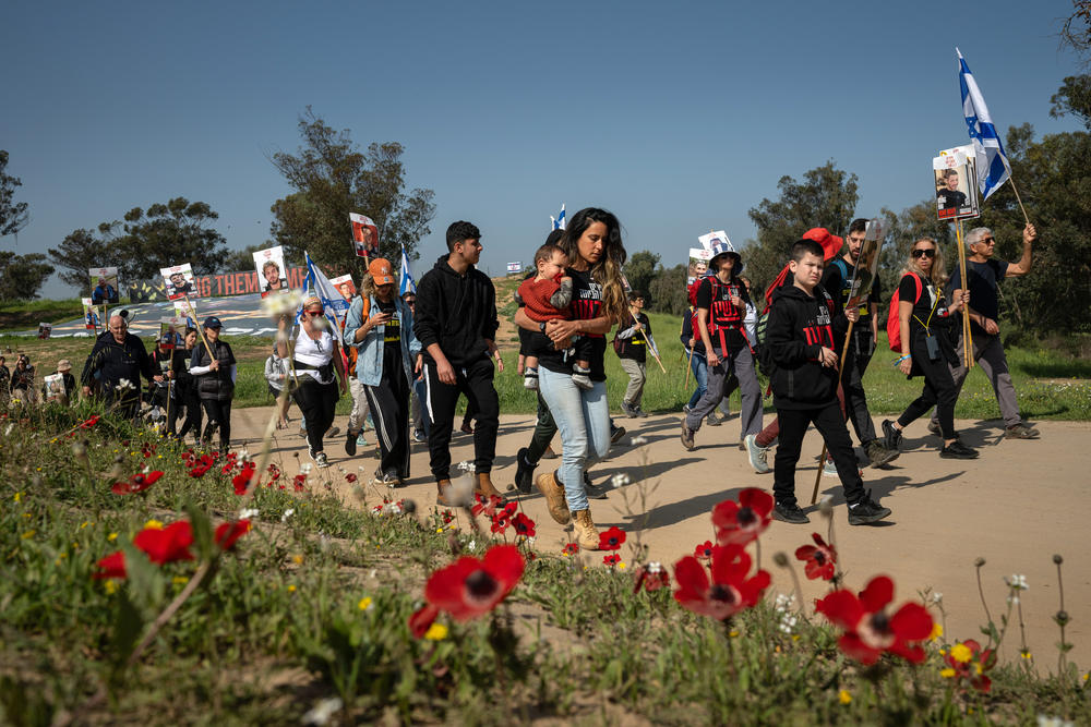 Relatives of the hostages who remain in captivity in Gaza and their supporters pass by red anemone flowers as they begin a four-day march from the site of the Hamas attack on the Nova music festival in Re'im, Israel, to Jerusalem on Feb. 28.