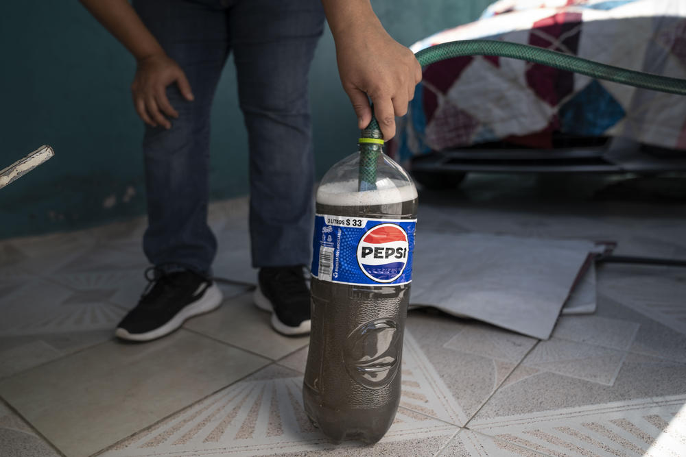 María Cristina Peláez fills a Pepsi bottle with dirty tap water at a neighbor's home in the municipality of Ecatepec, on the northern edge of Mexico City, on Sunday.