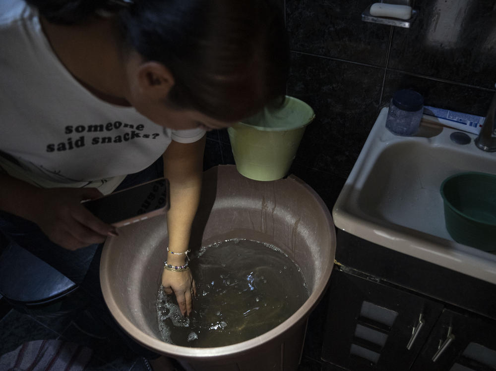 Sandra Martínez Martínez shows the dirty tap water she and her family are using as toilet water at her home in the municipality of Ecatepec, in the State of Mexico, on Sunday.
