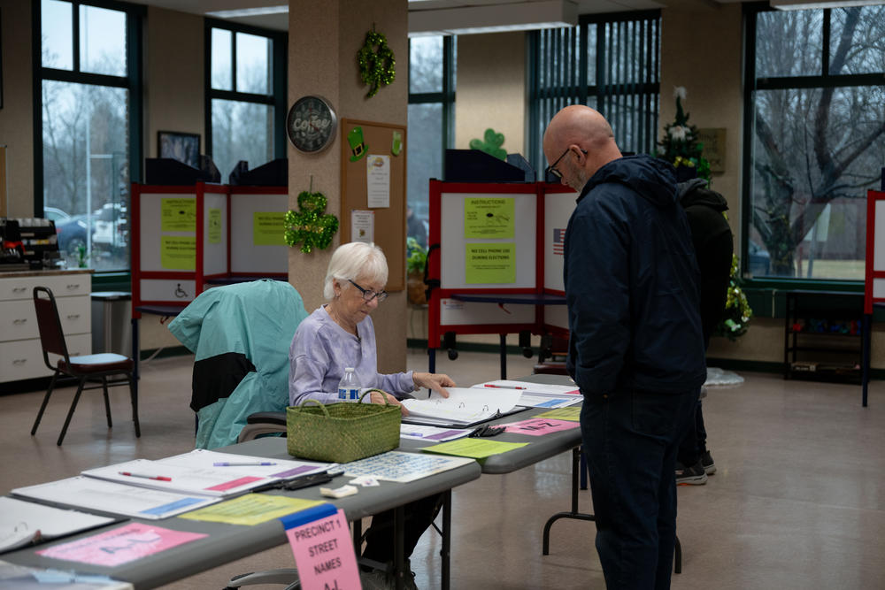 Poll worker Carol Laughlin, left, helps a voter with their ballot at the Southwick Senior Center polling place in Southwick, Mass.