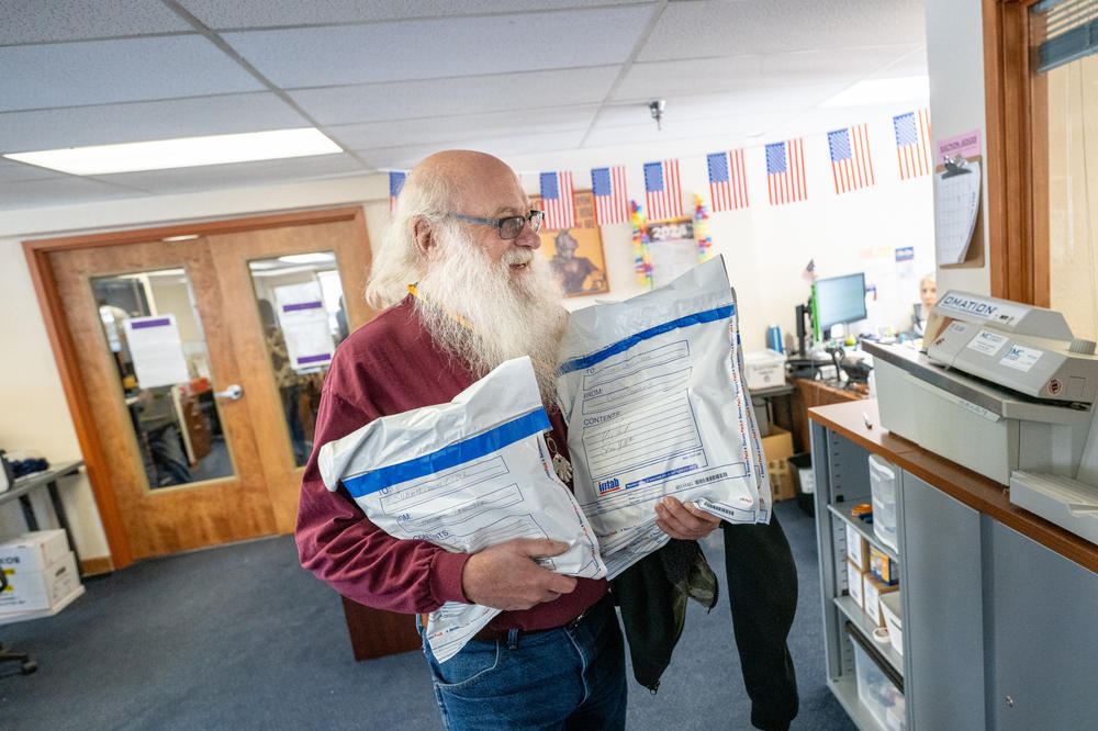 Bubba Haught carries sealed satchels of ballots from drop boxes into the Summit County Clerk and Recorder's Office in Breckenridge, Colo., for sorting and counting.