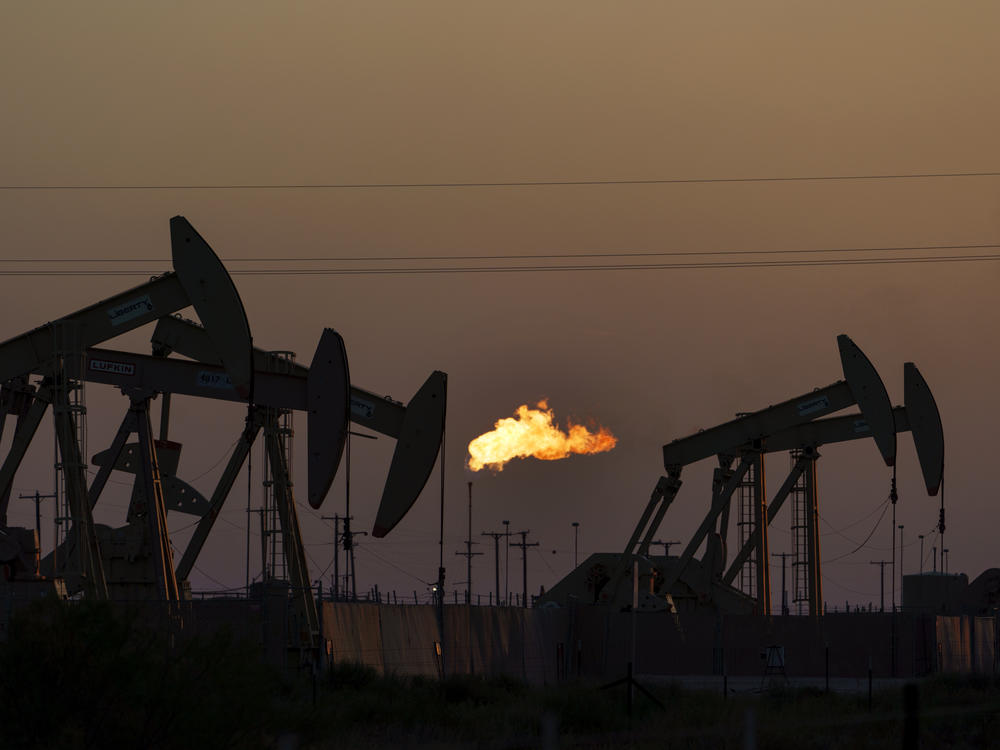 A flare burns off methane and other hydrocarbons as oil pumpjacks operate in the Permian Basin in Midland, Texas. Burning fossil fuels like coal, oil and natural gas is the main driver of global warming.