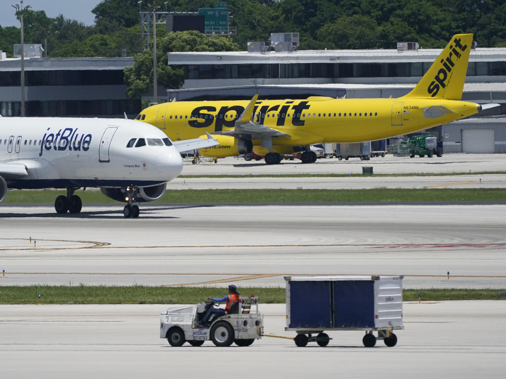 A JetBlue Airways Airbus A320, left, passes a Spirit Airlines Airbus A320 as it taxis on the runway, July 7, 2022, at the Fort Lauderdale-Hollywood International Airport in Fort Lauderdale, Fla. JetBlue and Spirit Airlines are ending their proposed $3.8 billion combination after a court ruling blocked their merger.