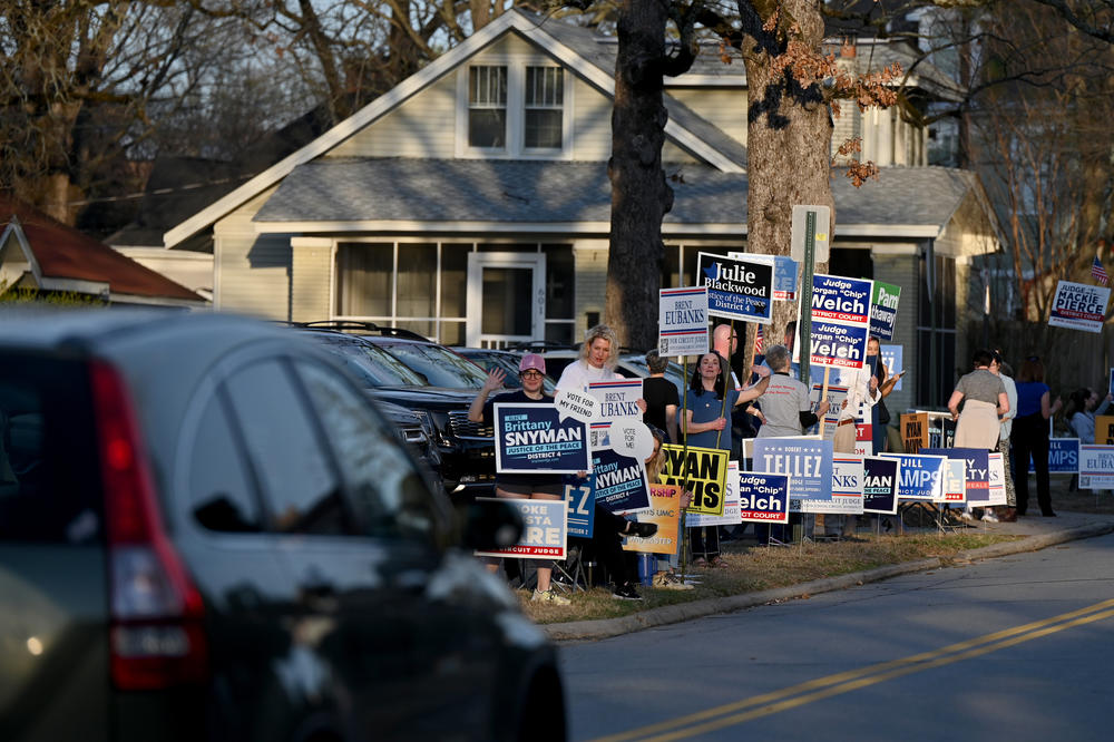 Supporters hold campaign signs on Super Tuesday outside of Pulaski Heights United Methodist Church in Little Rock, Ark.