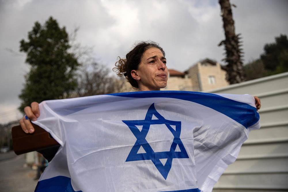 A woman holds an Israeli flag as family members of the hostages held in Gaza and their supporters approach Jerusalem on March 2.