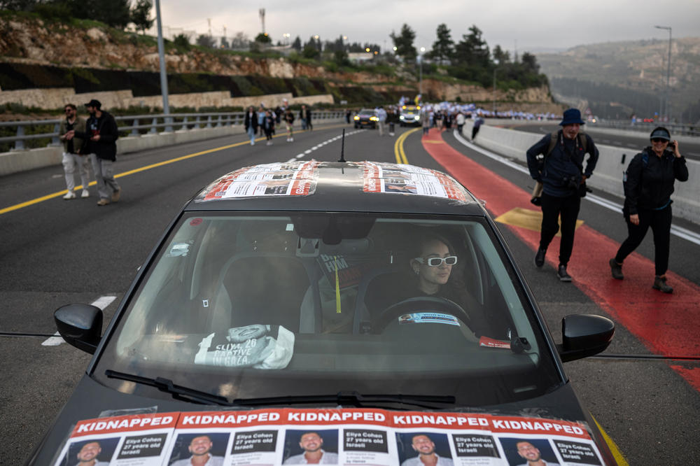 Michal Rahoom, whose best friend Eliya Cohen was kidnapped from the Nova music festival, drives a car covered in photos of him ahead of family members of the hostages and their supporters as they approach Jerusalem on the march's fourth and final day, on March 2.