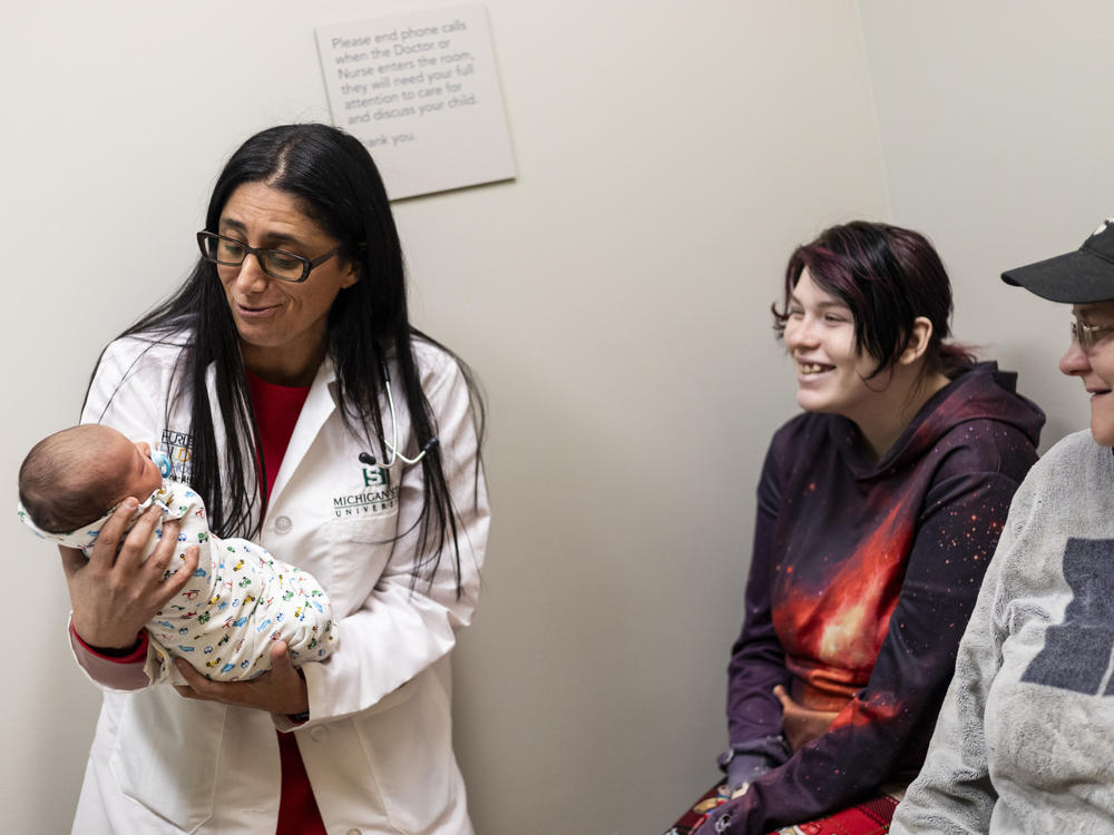 Dr. Mona Hanna-Attisha holds newborn baby Rowan, who was in for a wellness checkup with his 19-year-old mom, Hailey Toporek, and her mother, Heather Toporek, at the Hurley Children's Clinic in Flint.
