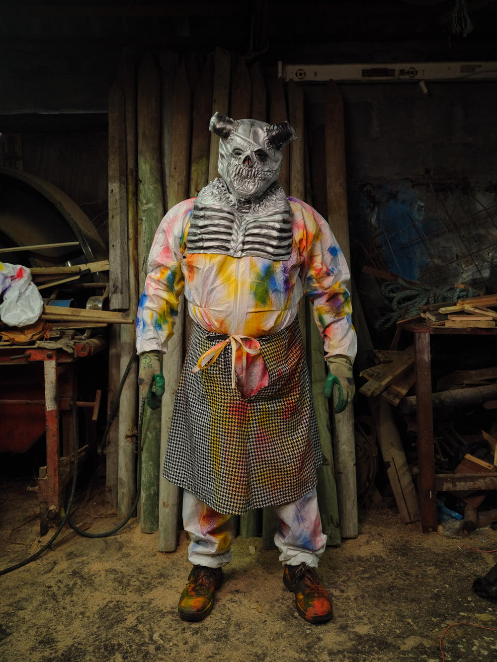 An Okalolie poses inside a clandestine changing room — a small sawmill. The Okalolies are part of a type of visiting custom known as mumming in which young men disguise themselves, visit homes and engage in playful pranks — mainly at Christmas and on New Year's Eve — that have existed in Europe for the past 500 years.