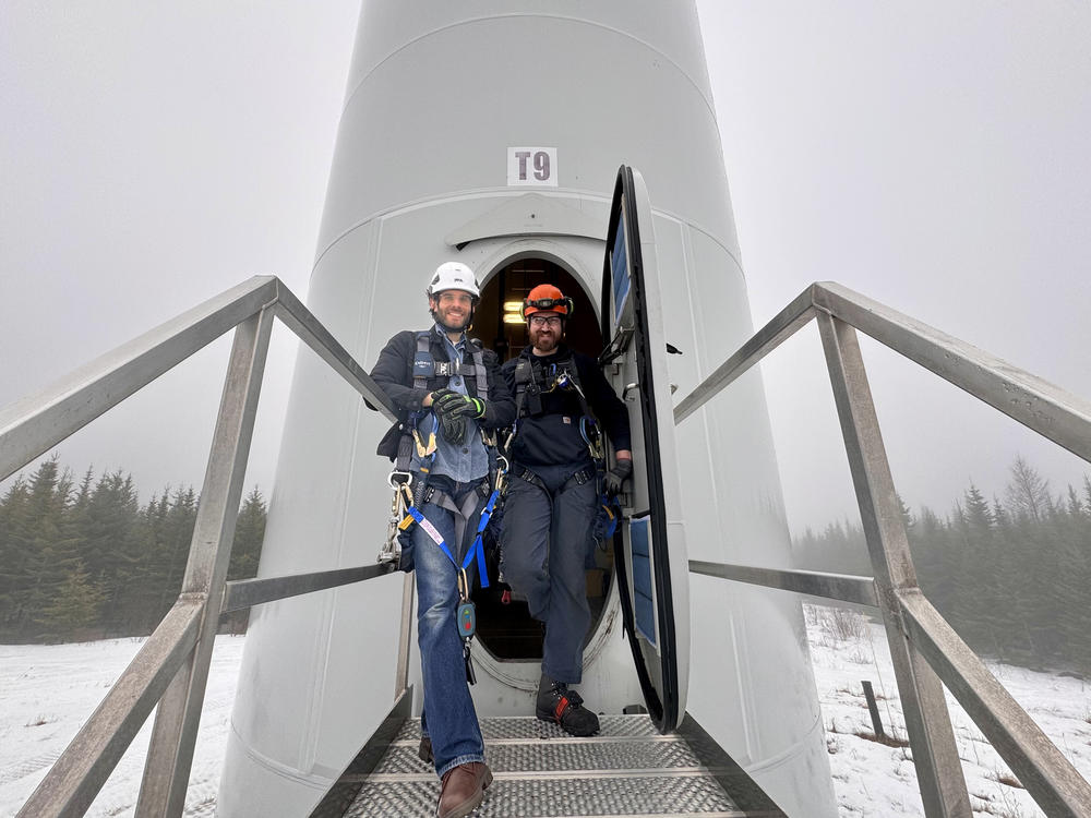 Reporter Darian Woods and wind turbine technician Konnor Therriault at the base of a Vestas wind turbine in Bingham, Maine. (Photo by Matthew Copeman)