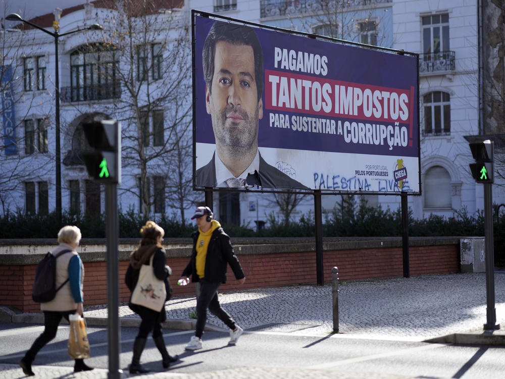 People walk by a billboard for Andre Ventura, leader of populist radical right party Chega (in English, Enough) with the words, 
