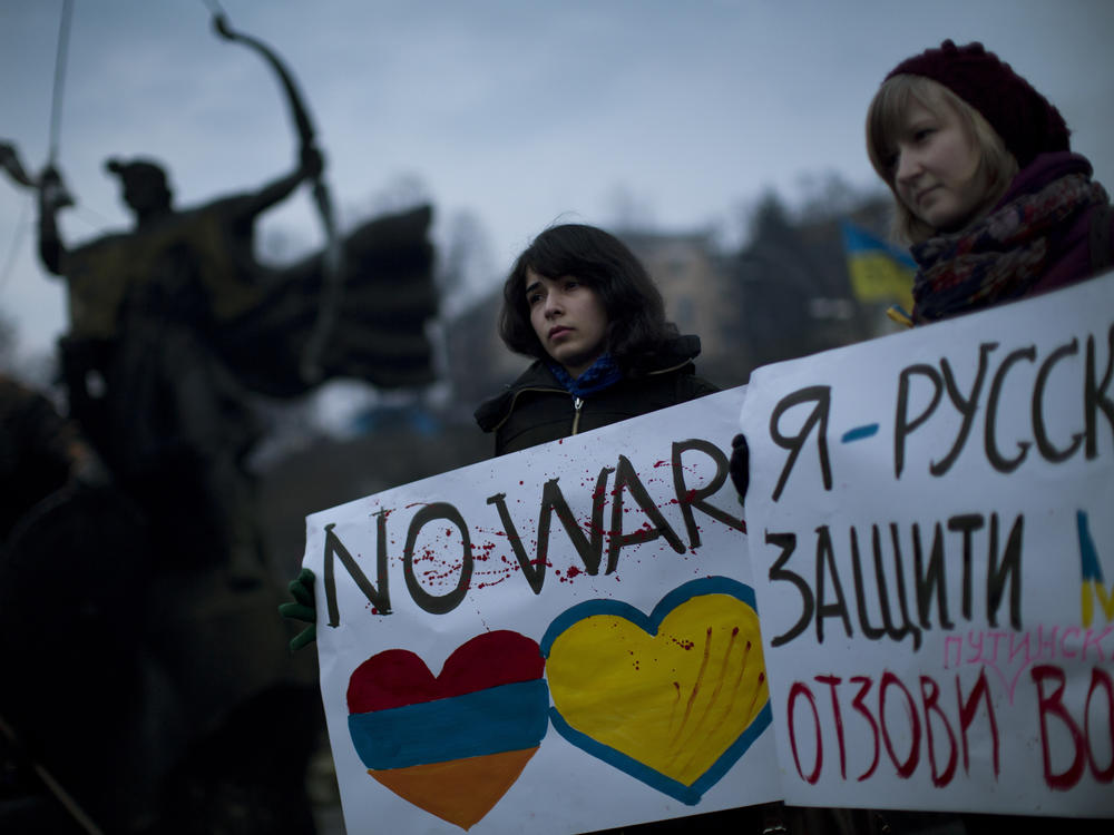 Two Ukrainian citizens hold up posters against Russia's military intervention.