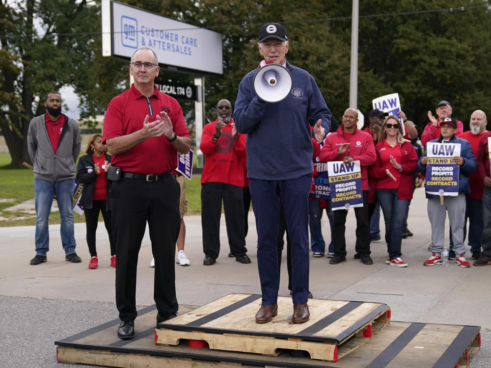 President Biden speaks to striking United Auto Workers members and their president, Shawn Fain, after walking the picket line on Sept. 26, 2023.