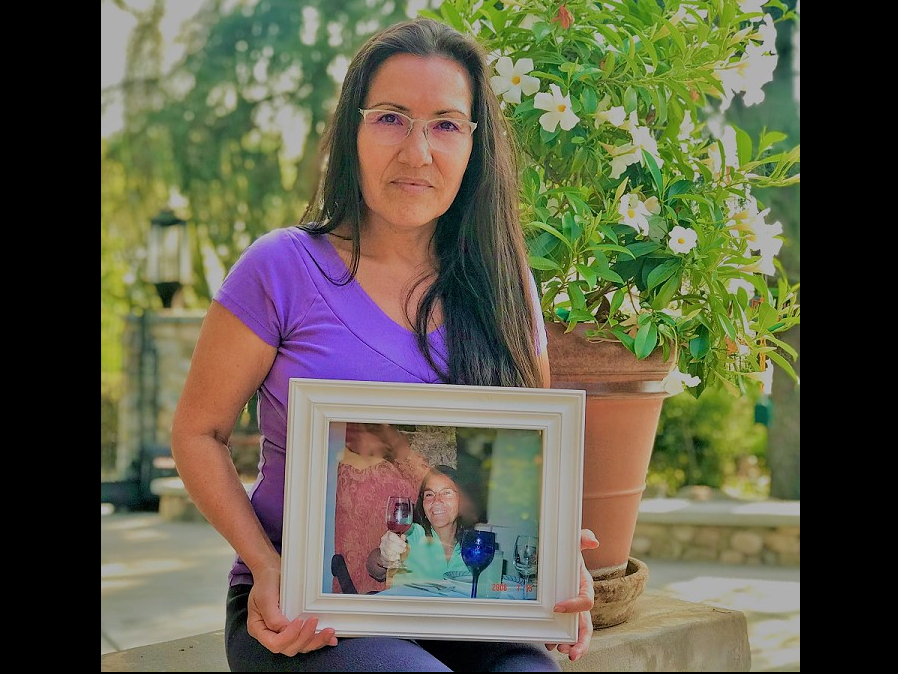 Maria E. Garay-Serratos holds a framed photograph of her mother, who died after suffering decades of domestic violence. Scientists are trying to understand how domestic violence damages the brain.