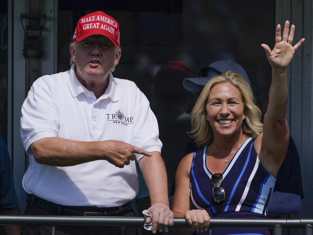 In this file photo, Rep. Marjorie Taylor Greene, R-Ga., waves while former President Donald Trump points to her at his golf course in 2022, in Bedminster, N.J.