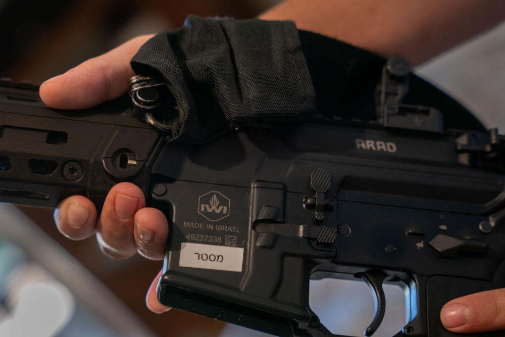 Ori Kahan, 21, a volunteer with an armed security squad in the central Israeli community of Rishpon, holds an assault rifle he keeps under his mattress in his bedroom.