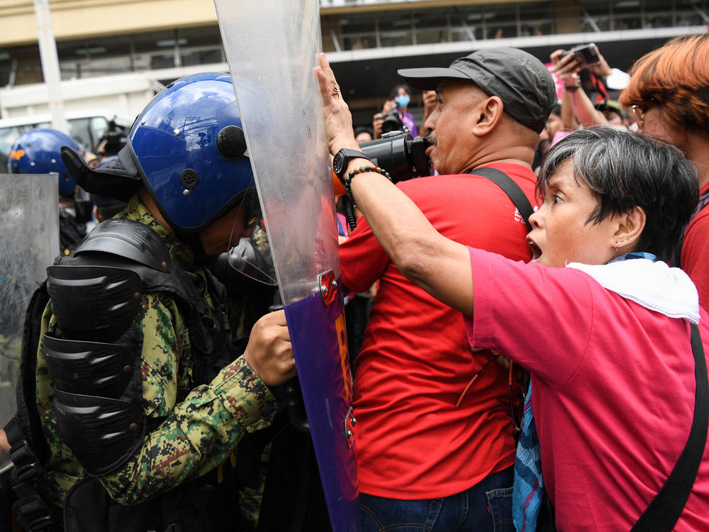 A woman activist tries to push back a riot police officer who blocked their march towards the Malacanang Palace during a protest to mark International Women's Day in Manila.