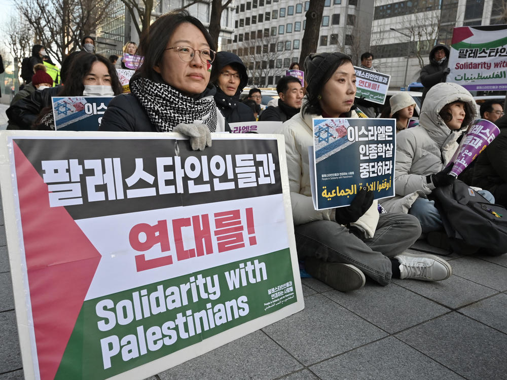 Activists supporting Palestinian women hold placards reading 