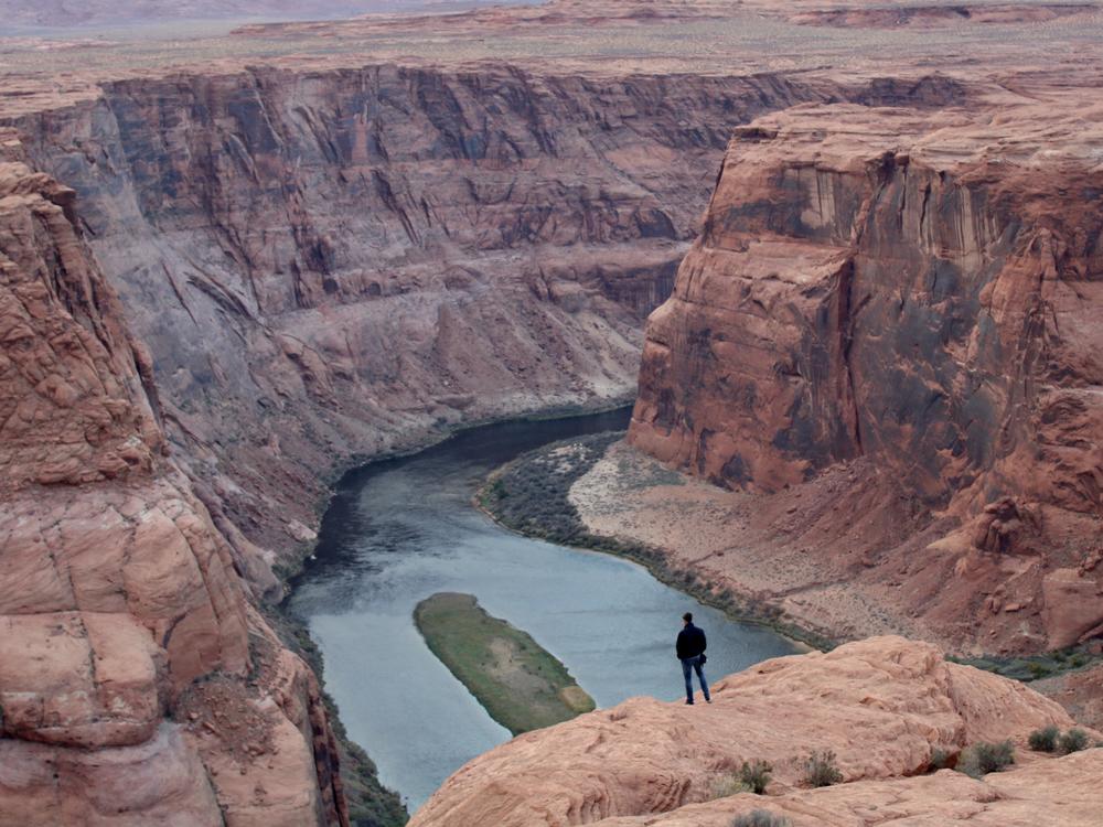 A man looks out over the Colorado River near Page, Arizona on Nov. 2, 2022. The seven states that manage the river are divided about how to account for the impacts of climate change in new plans about sharing its water.