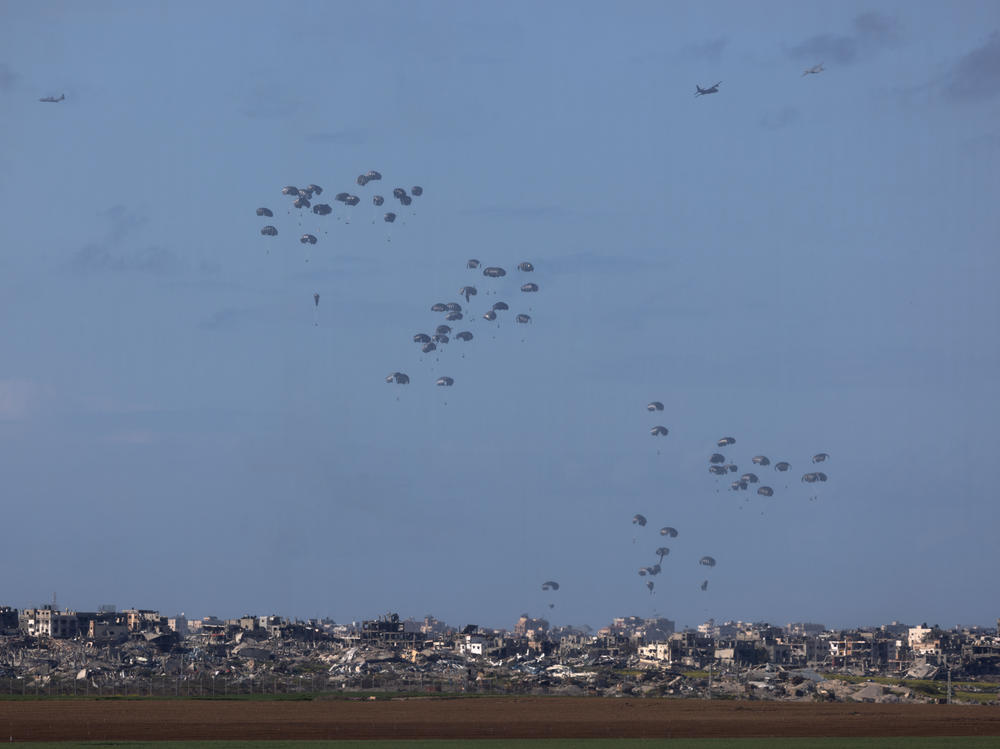 Humanitarian aid falls from planes over northern Gaza as seen from Israel's southern border with the Gaza Strip on March 7.