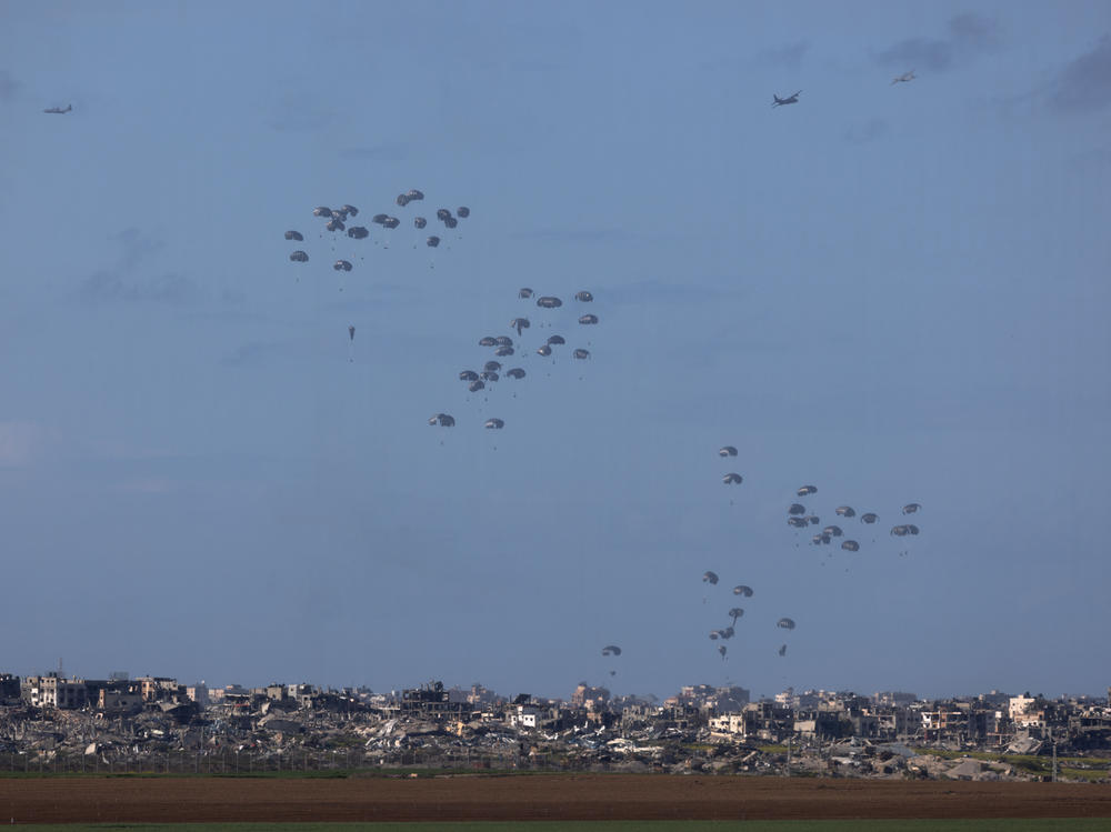 Humanitarian aid falls from planes over northern Gaza as seen from Israel's southern border with the Gaza Strip on March 7.