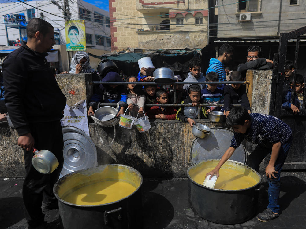 Displaced Palestinians gather to receive food at a donation point in Rafah on Thursday, March 7.