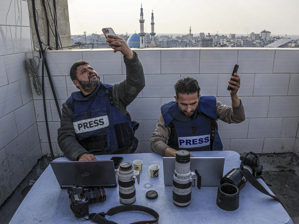 Palestinian journalists attempt to connect to the internet using their phones in Rafah on the southern Gaza Strip on Dec. 27, 2023, amid continuing battles between Israel and Hamas.