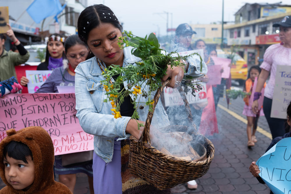 A young woman holds the rue plant, a symbol of strength, and lights up incense to cleanse the path women march.
