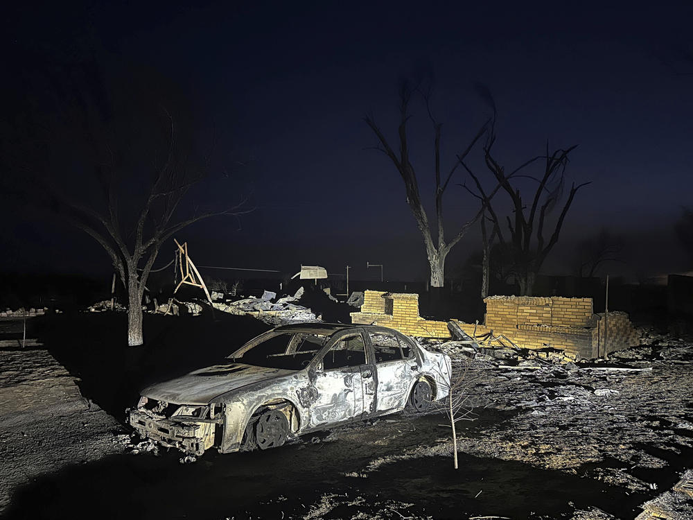 A charred vehicle sits near the ruins of a home after the property was burned by the Smokehouse Creek Fire.