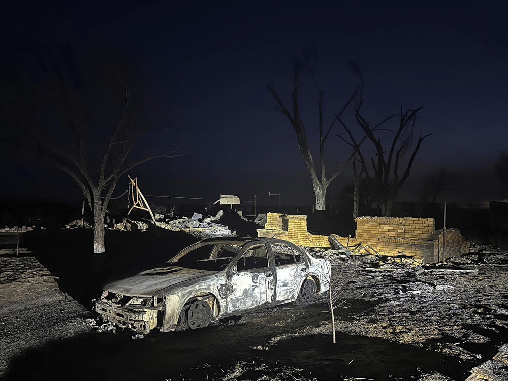 A charred vehicle sits near the ruins of a home after the property was burned by the Smokehouse Creek Fire.