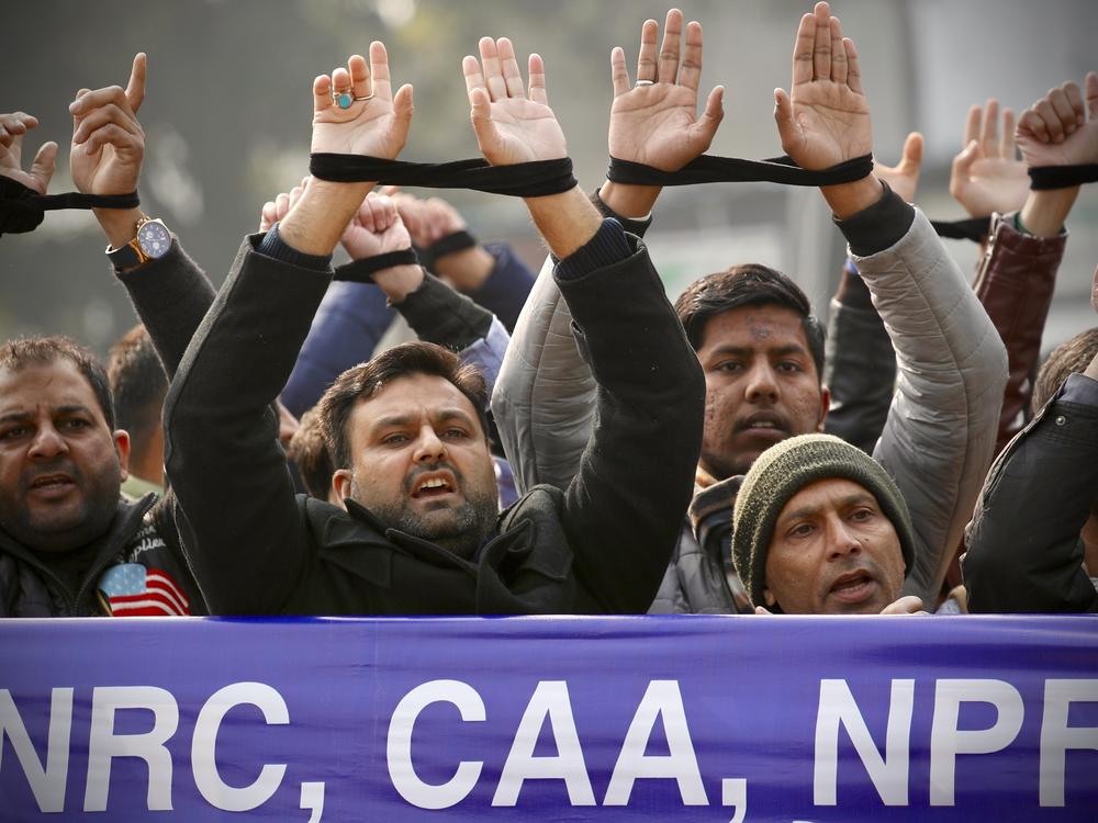 Indians raise their tied hands and shout slogans during a protest against the Citizenship Amendment Act in New Delhi, India, Dec. 27, 2019. Prime Minister Narendra Modi's government on Monday announced rules to implement a 2019 citizenship law that critics say is discriminatory against Muslims, weeks before the Hindu nationalist leader will seek a third term in office.