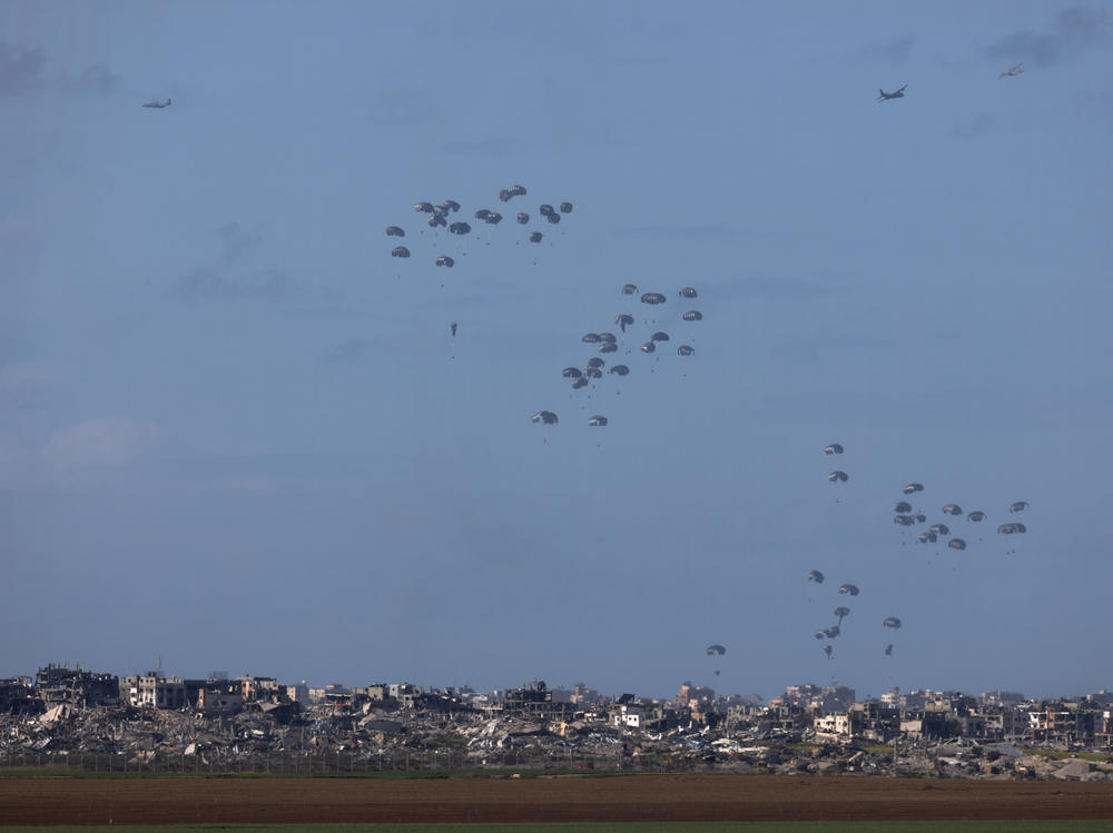 Humanitarian aid falls from planes over northern Gaza as seen from Israel's southern border with the Gaza Strip on March 7, 2024.