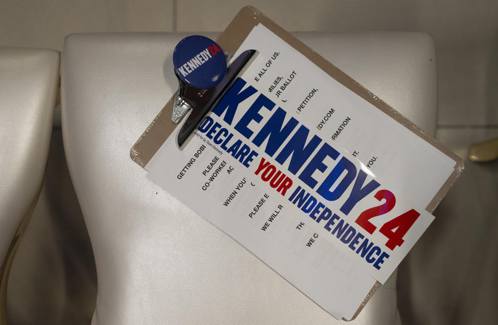 A view of a Kennedy 2024 board, sticker and button during a campaign rally in Phoenix on Dec. 20, 2023.
