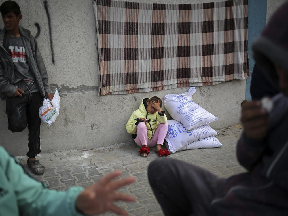A displaced Palestinian girl sits next to sacks of humanitarian aid at the distribution center of the United Nations Relief and Works Agency for Palestine Refugees (UNRWA), in Rafah in the southern Gaza Strip on March 3.
