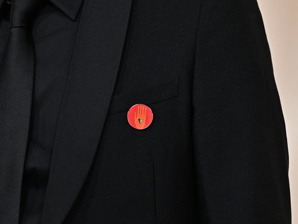 Nadim Cheikhrouha, producer for the Oscar-nominated documentary <em>Four Sisters</em>, wears an Artists4Ceasefire pin as he attends the Academy Awards on Sunday. The pin features a hand with a black heart in the middle of it.