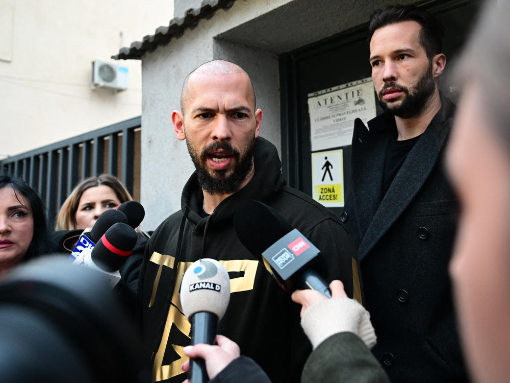 British U.S. former professional kickboxer and controversial influencer Andrew Tate (center) and his brother Tristan Tate (back right) speak to journalists after having been released from detention in Bucharest, Romania, Tuesday.
