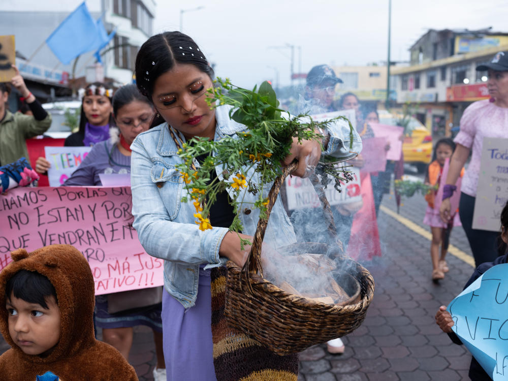 Una mujer joven sostiene la planta de ruda, que es vista como un símbolo de fuerza, mientras enciende incienso para limpiar el camino que recorren las mujeres.