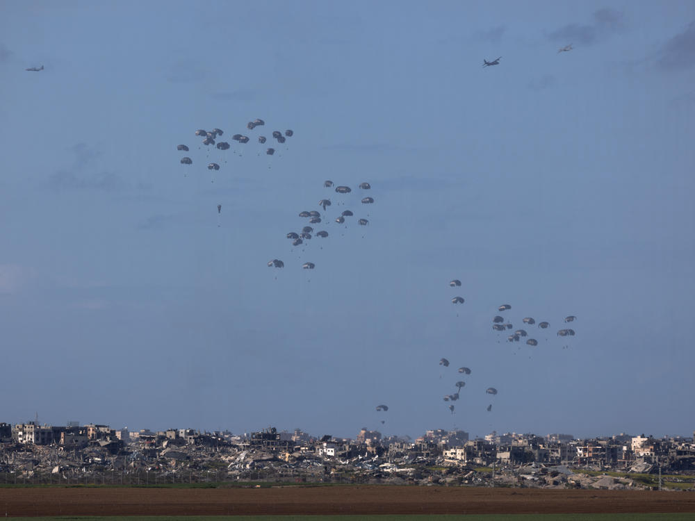 Humanitarian aid falls from planes over northern Gaza as seen from Israel's southern border with the Gaza Strip on March 7.