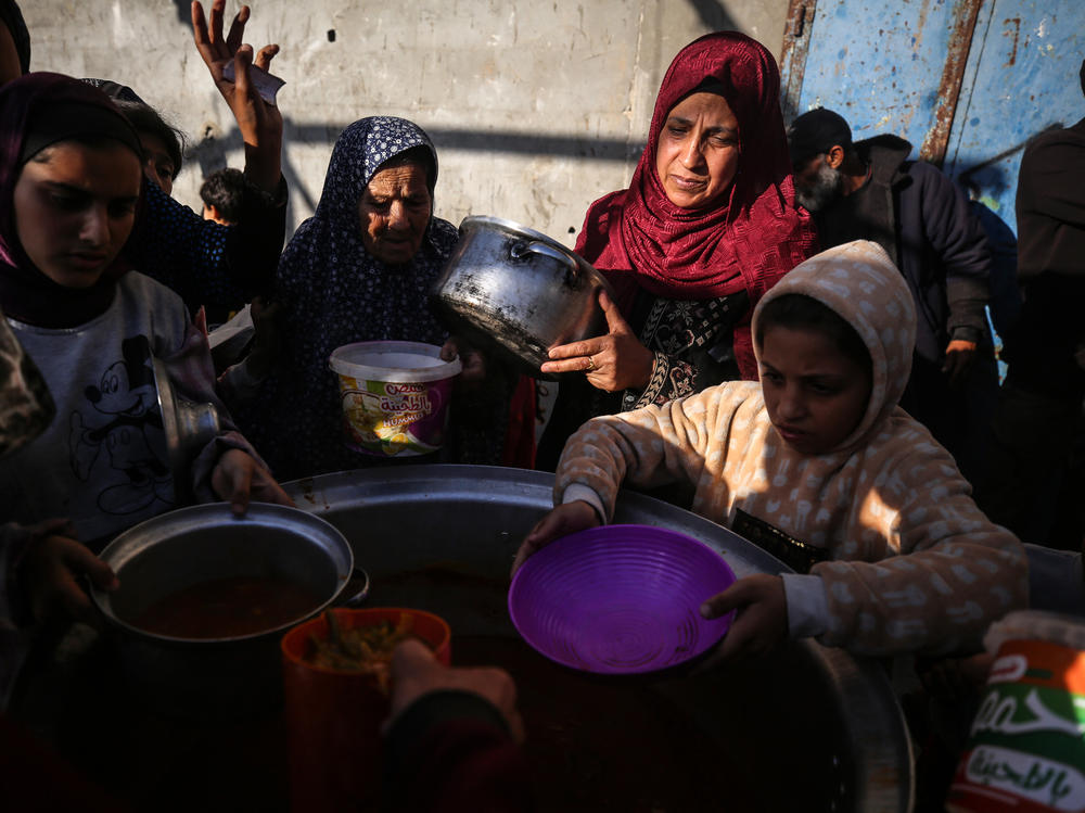 Displaced Palestinians gather to receive food donated by a charity before an iftar meal, the breaking of fast, on the second day of the Muslim holy fasting month of Ramadan, in Deir al-Balah, central Gaza Strip, Tuesday, amid ongoing battles between Israel and the militant group Hamas.