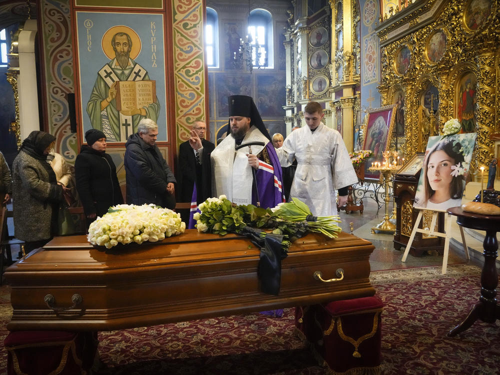 A priest prays over the coffin of Oleksandra 