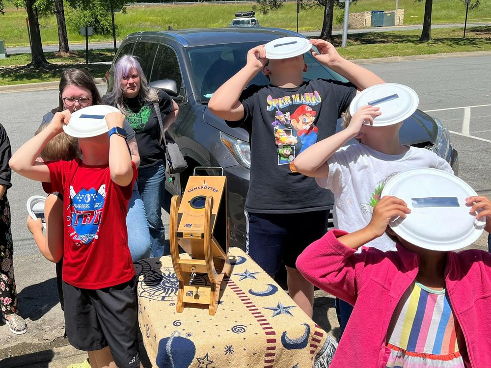 Children use solar filters to safely view the sun in North Little Rock, Ark., in May. The event is part of the Central Arkansas Astronomical Society's public education effort to prepare for this year's April 8 total solar eclipse.