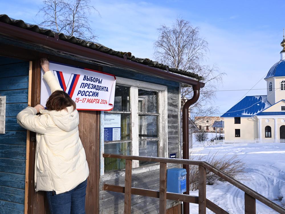A member of a local election commission prepares a polling station with a sign that reads 