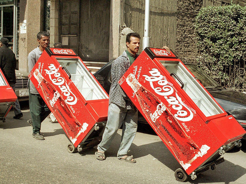 Egyptian workers push Coca-Cola refrigerators through a Cairo street in 2000.