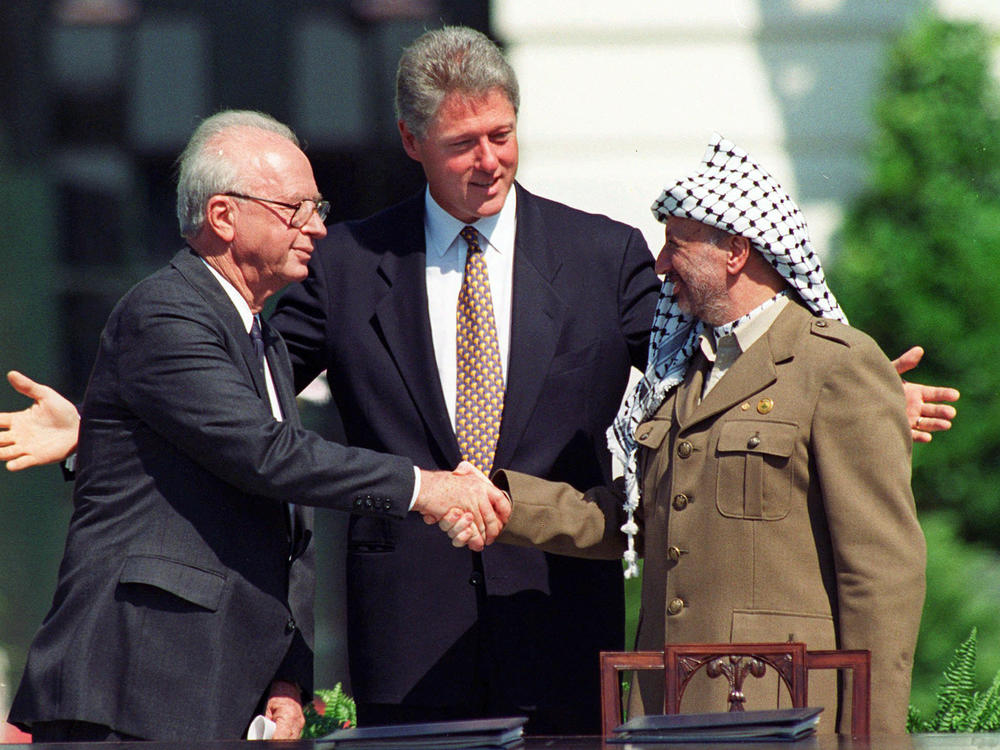 Israeli Prime Minister Yitzhak Rabin (left) and Palestinian leader Yasser Arafat shake hands, marking the signing of the peace accord between Israel and the Palestinians, as U.S. President Bill Clinton looks on, in Washington, D.C., on Sept. 13, 1993.