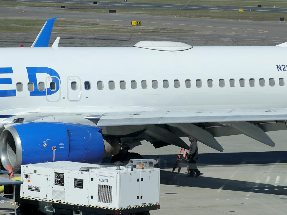 A Medford Jet Center worker walks under a United Boeing 737-824 that landed at Rogue Valley International-Medford Airport from San Francisco with a missing panel on Friday in Medford, Ore.