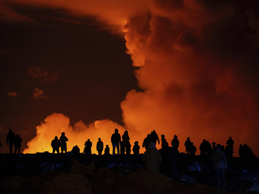 Spectators watch plumes of smoke from volcanic activity between Hagafell and Stóri-Skógfell, Iceland, Saturday, March 16, 2024.