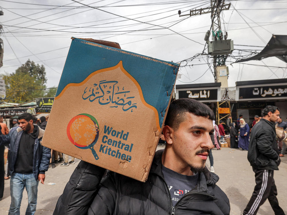 A man carries a cardboard box of food aid provided by nonprofit organization World Central Kitchen in Rafah, in southern Gaza, on March 17, amid the conflict between Israel and the militant group Hamas.